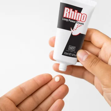 A pea-sized amount of Rhino Long Power Cream on a fingertip, the 30 ml tube held above it