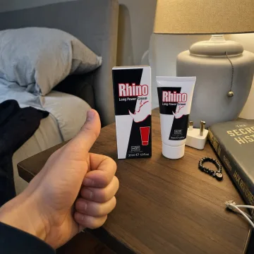 The Rhino Long Power Cream carton and tube on a bedside table next to a lamp and a book